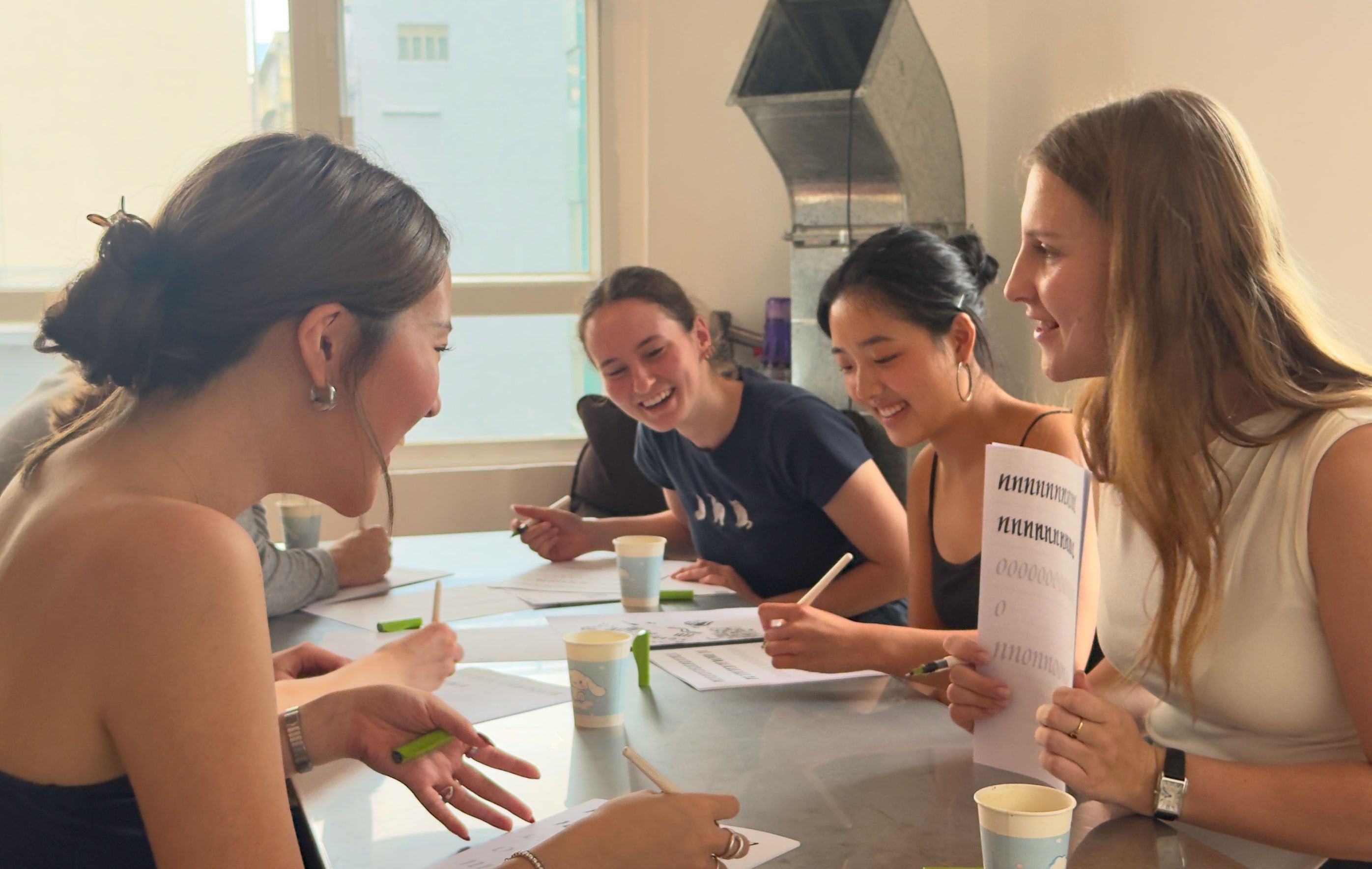 four participants practising calligraphy together around a workshop table