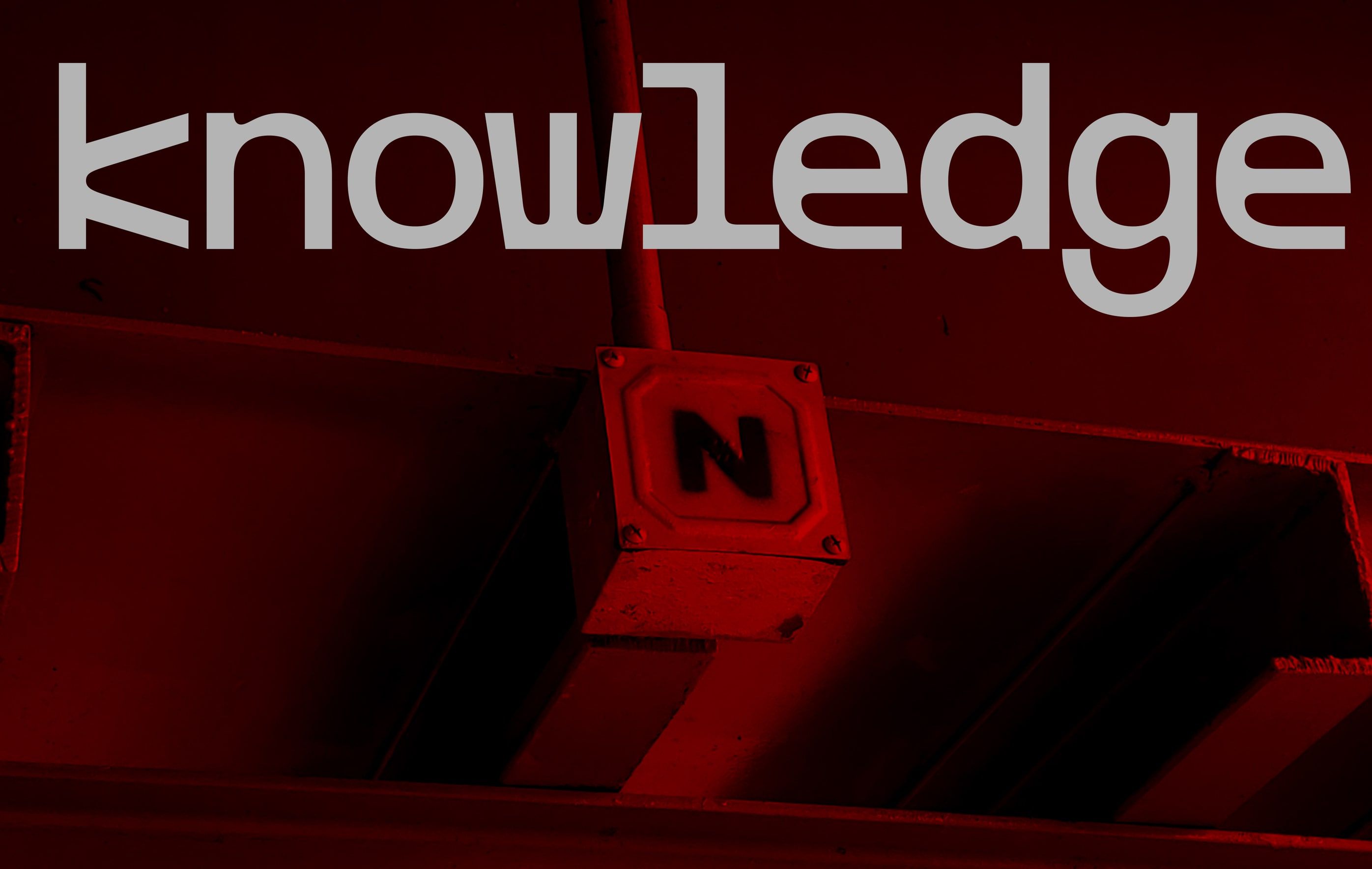 the word knowledge over a red-lit industrial sign marked n