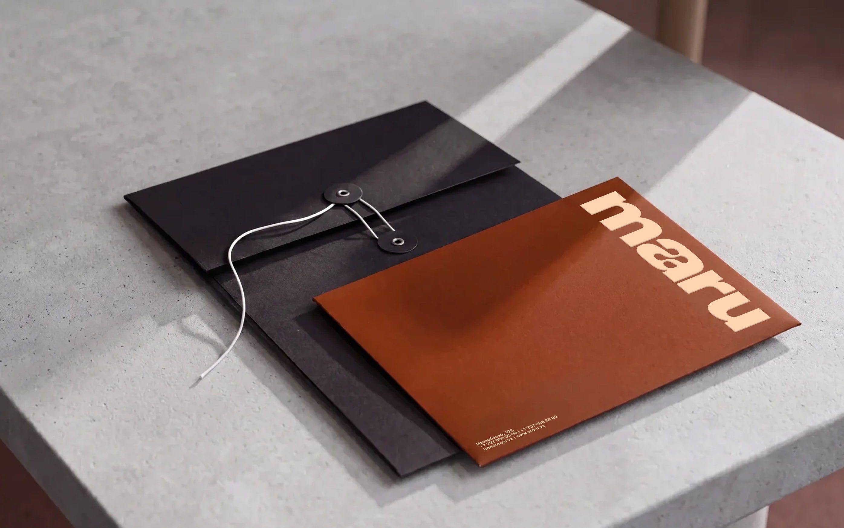 black string-and-button envelope and rust-coloured maru stationery